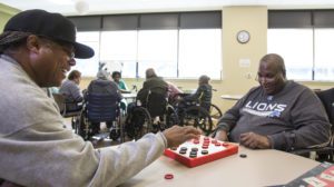 Older adults in an affordable senior living facility play checkers.